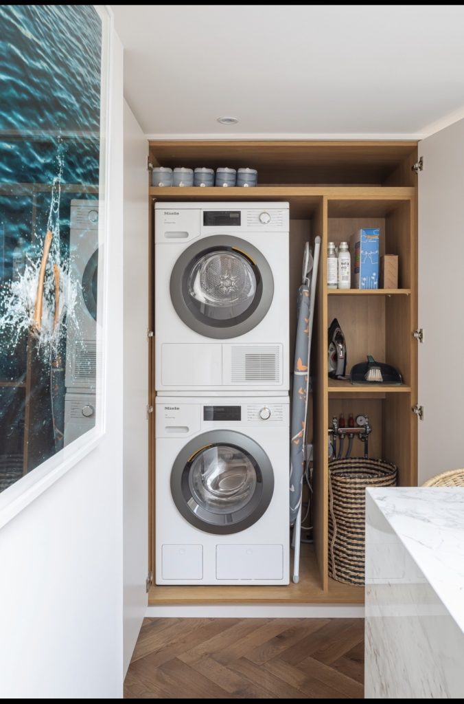 Open shelving above stacked washer and dryer