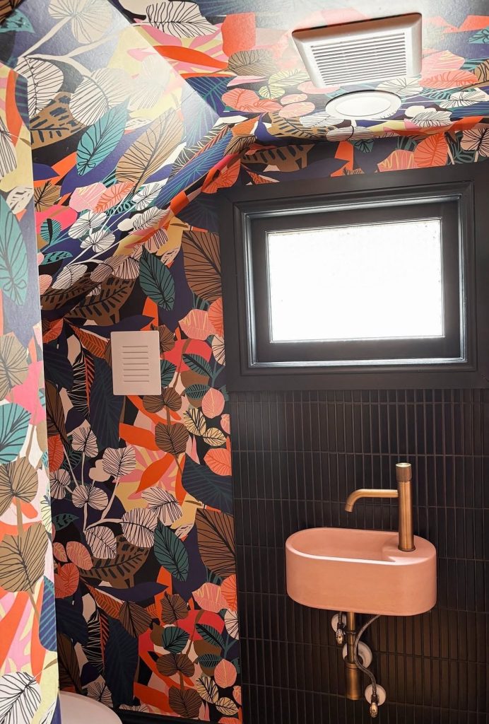 Tiny Half Bathroom With Wallpaper on Its Slanted Ceiling